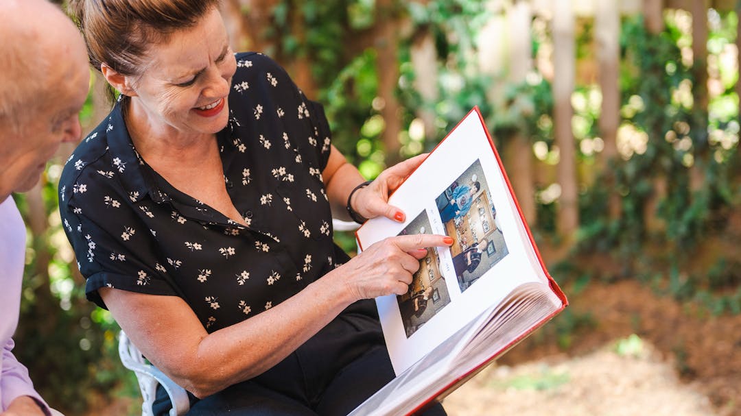 carer and older man looking at photo album together