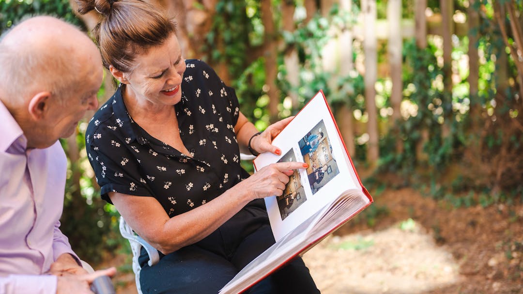 carer and older man looking at photo album together