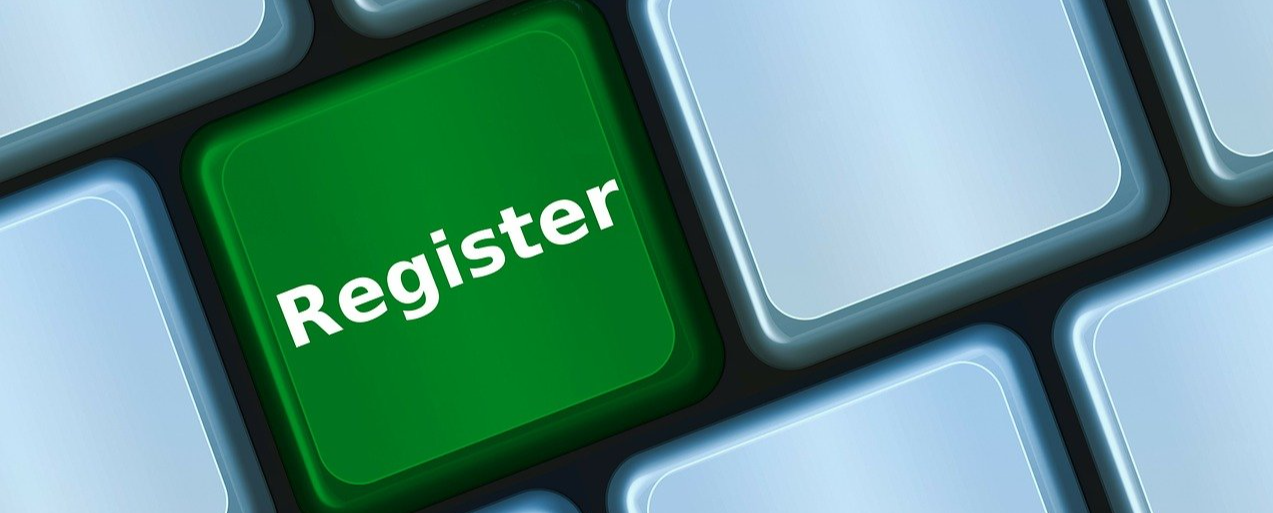 A white computer keyboard with a green key that says register