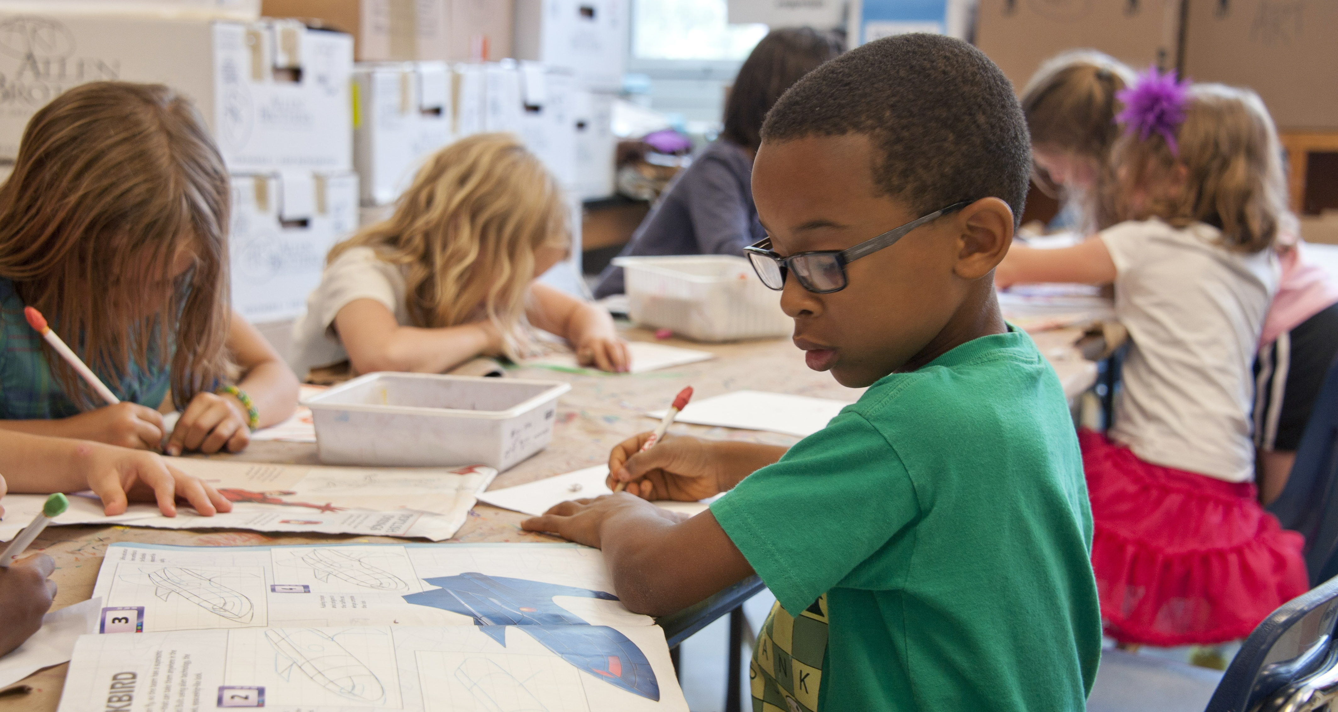 6 children sitting around a group of tables doing craft at school