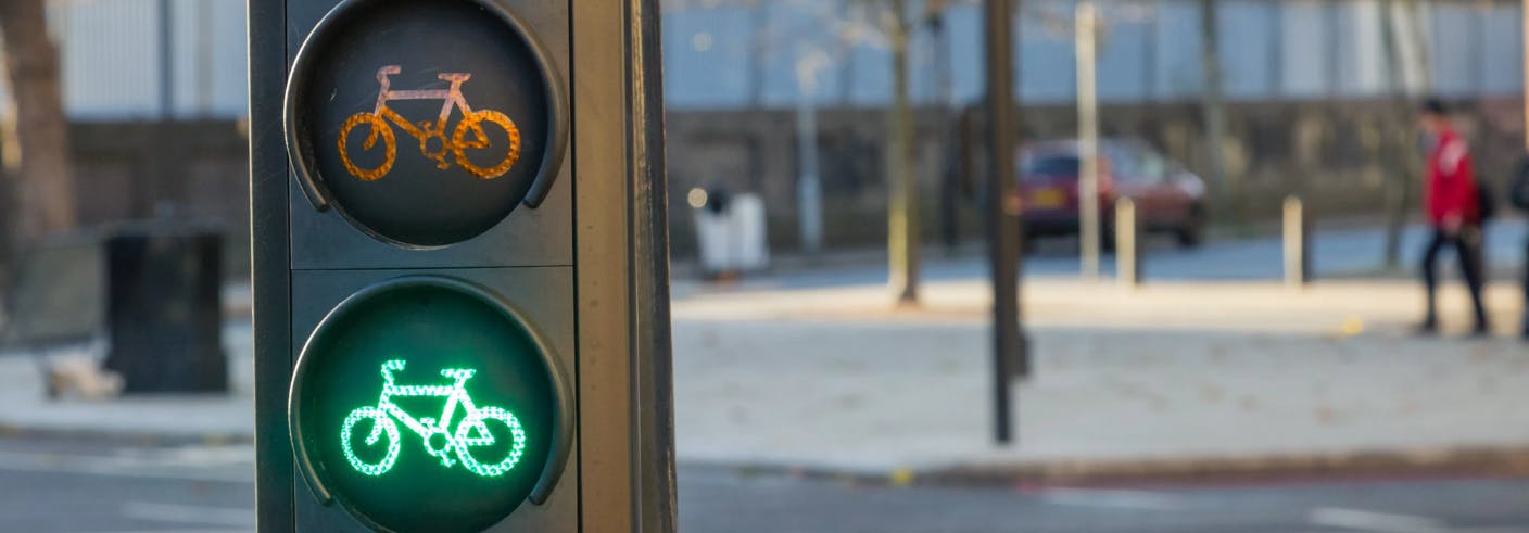 Traffic lights with green bicycle signal showing, in front of a road with bicycle makings on it.