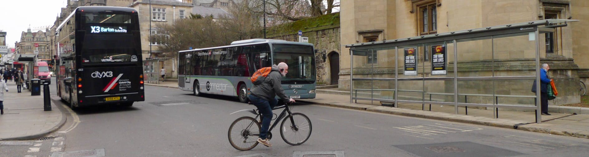 Cyclist crossing road with buses parked