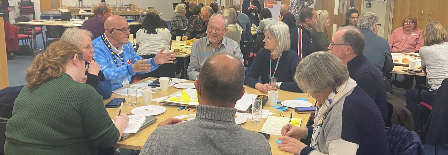 A group of councillors at the Oxfordshire Council Charter Summit held in October 2023. They are sat around a table talking.