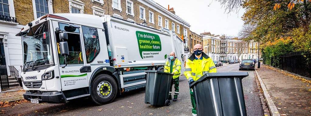 Two workers with bins standing in front of an electric refuse vehicle on a street in Islington