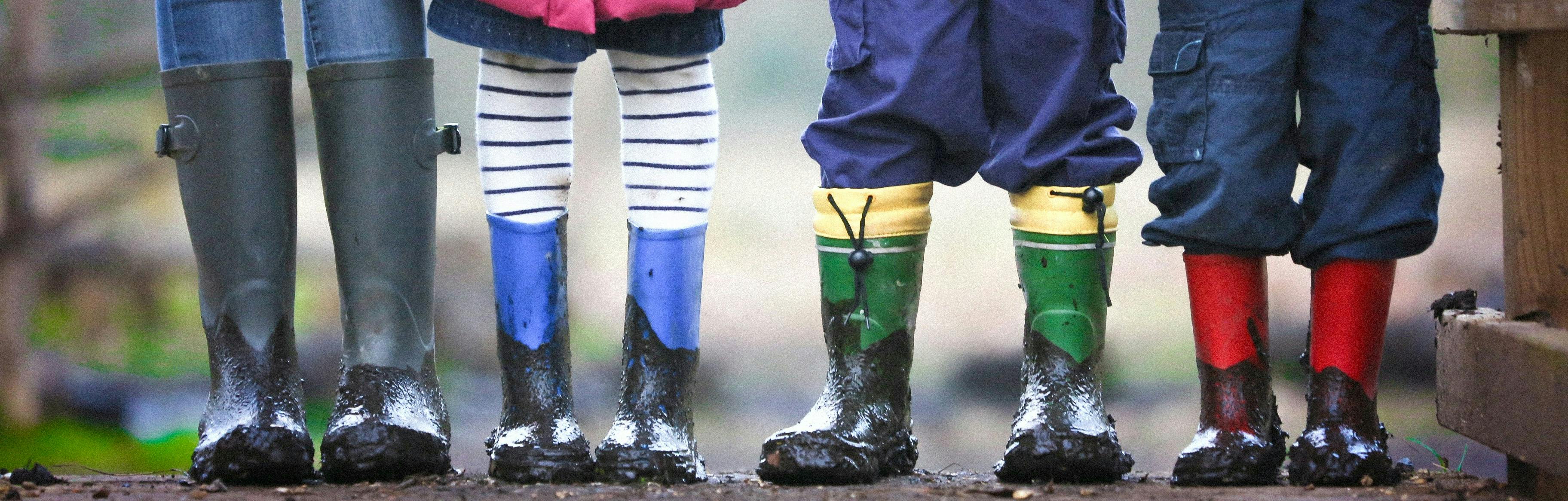 Children standing in line wearing wellington boots