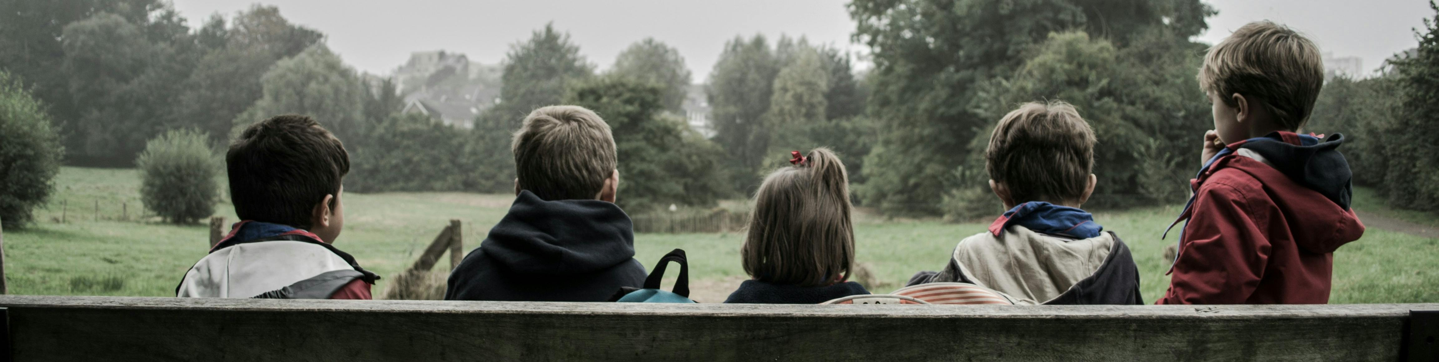 Children sat on a bench looking at a park