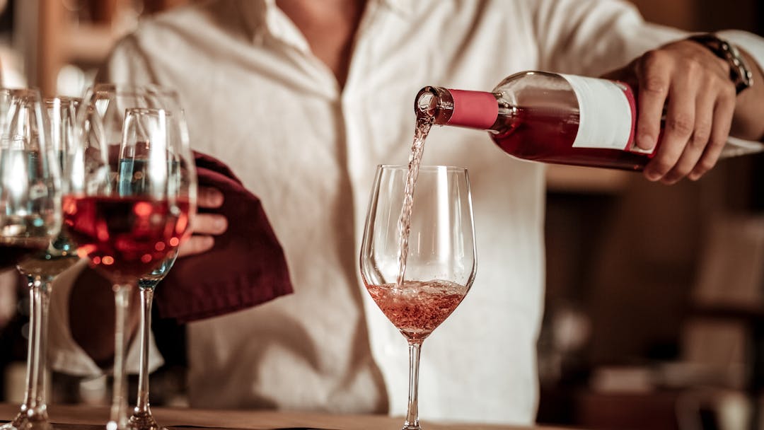 Image shows wine being poured into a glass