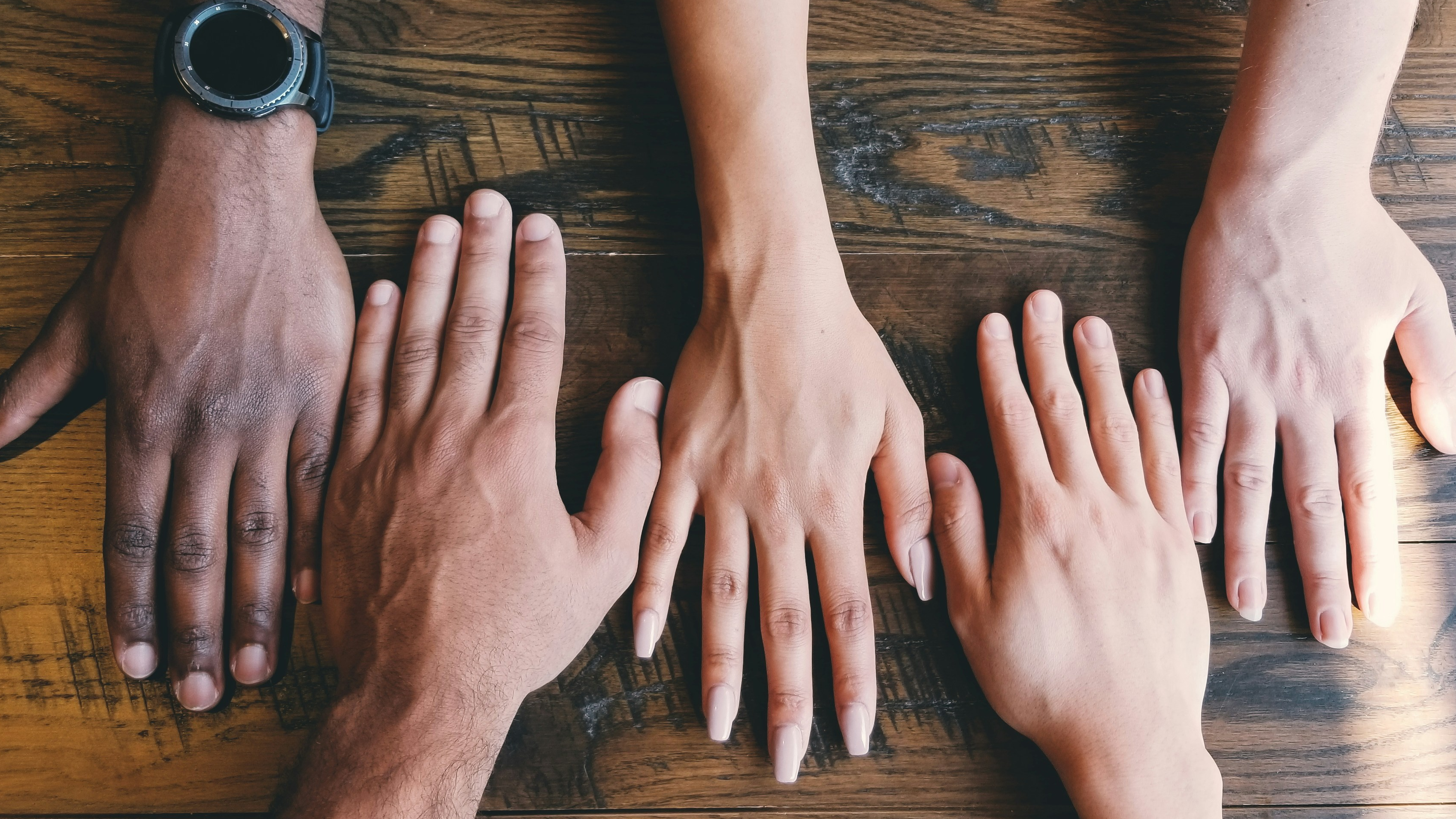 People's hands put side by side on a table
