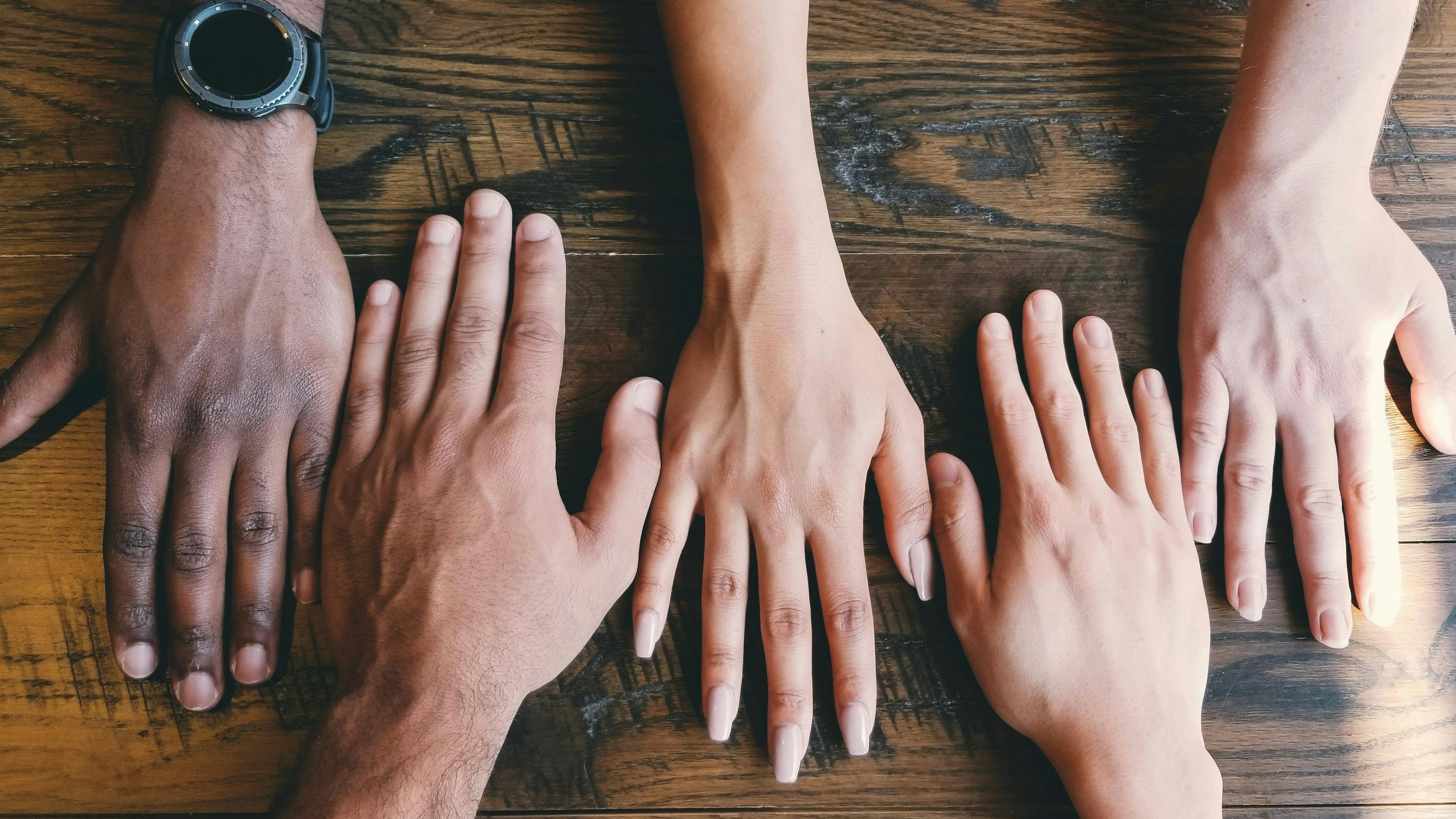 People's hands put side by side on a table