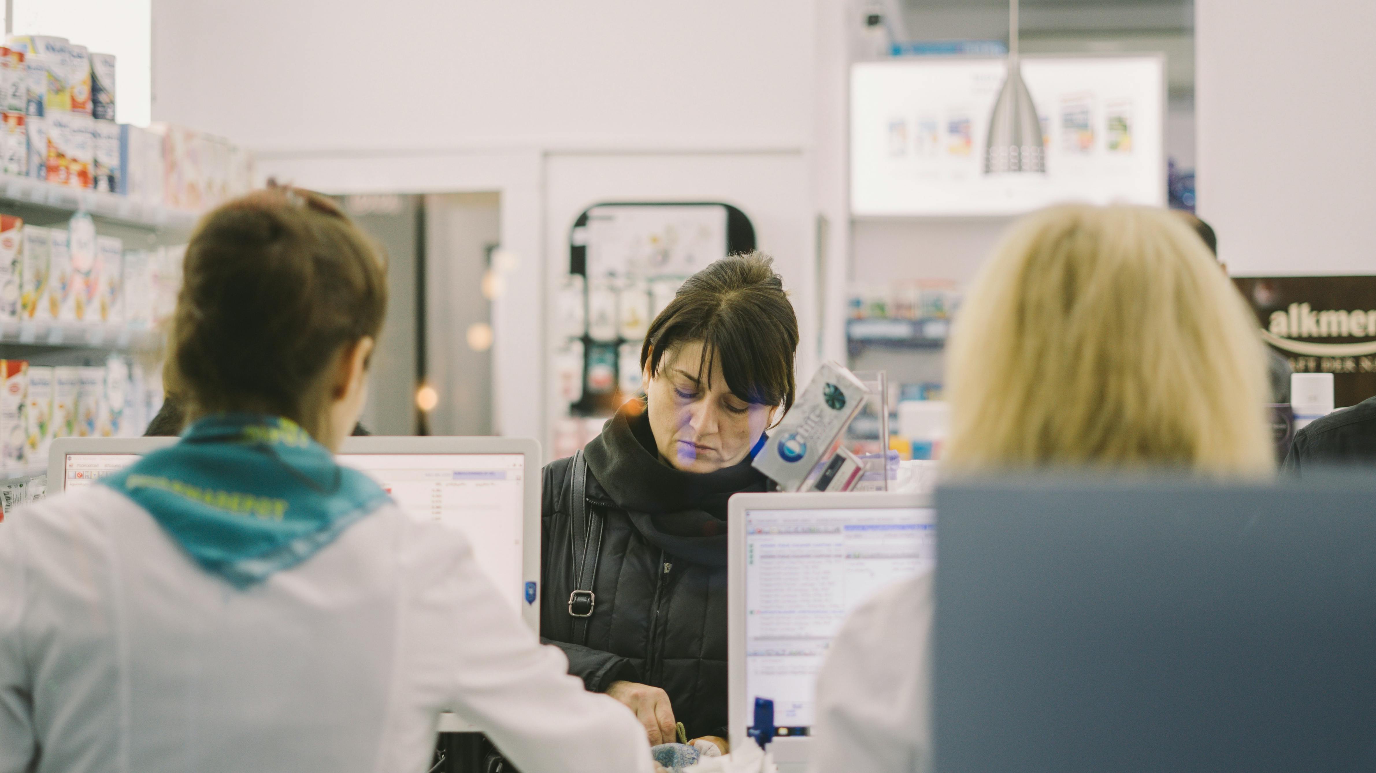 Customers being served at a pharmacy counter