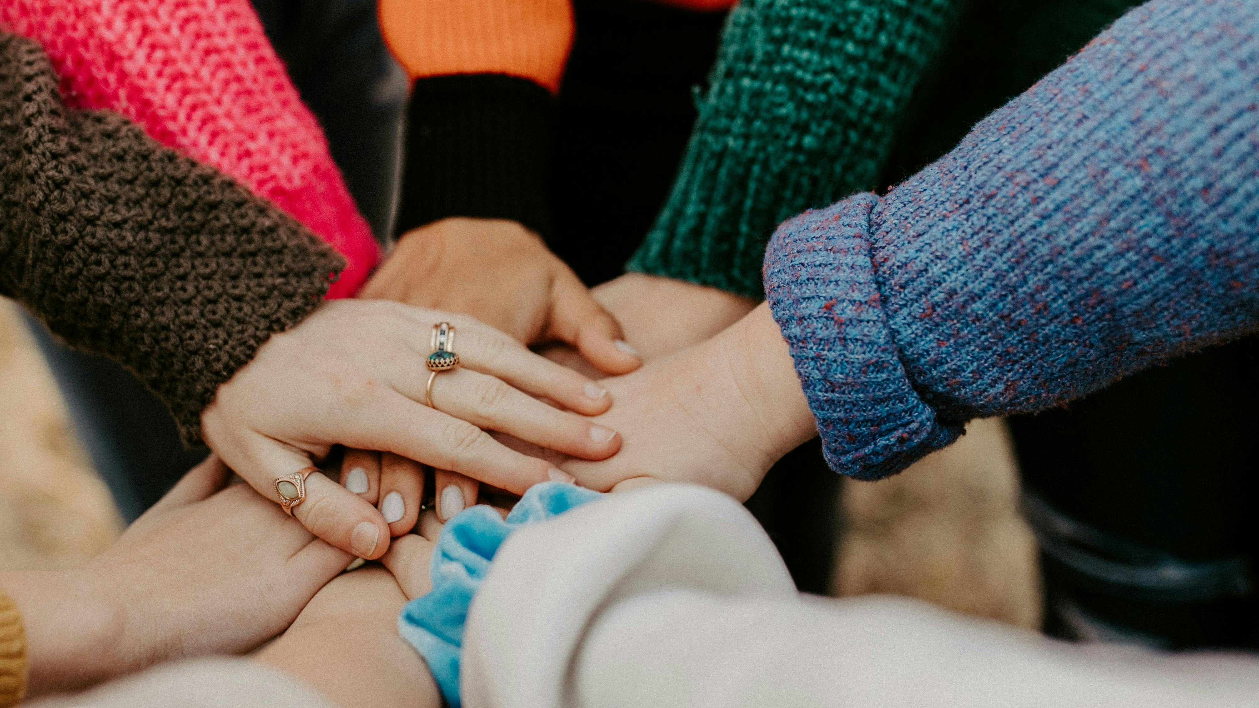 Group of young people putting their hands on top of each other