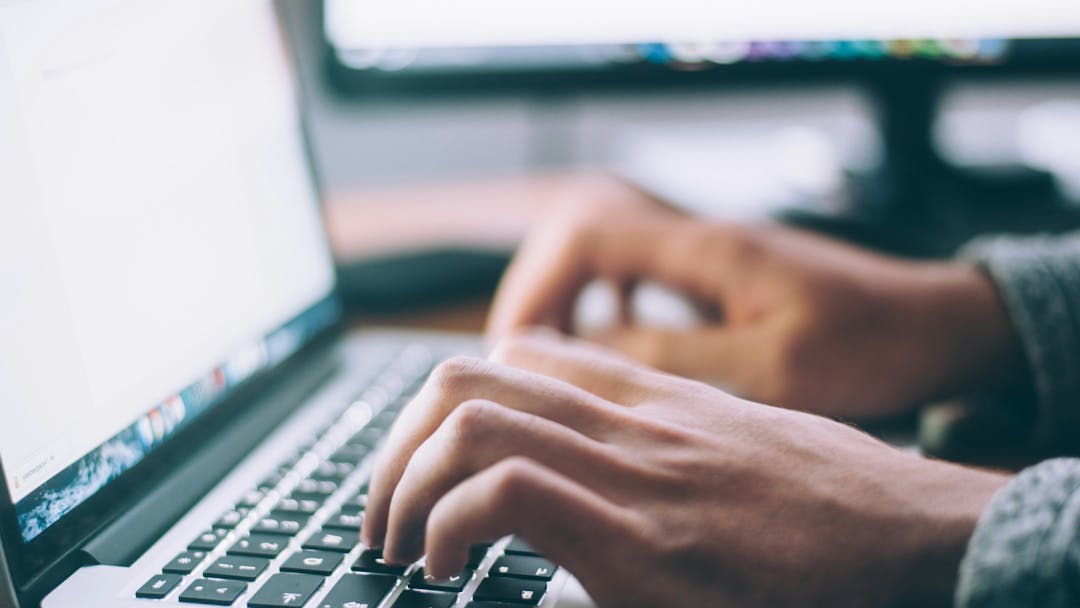 Photograph of somebody typing on a laptop. 