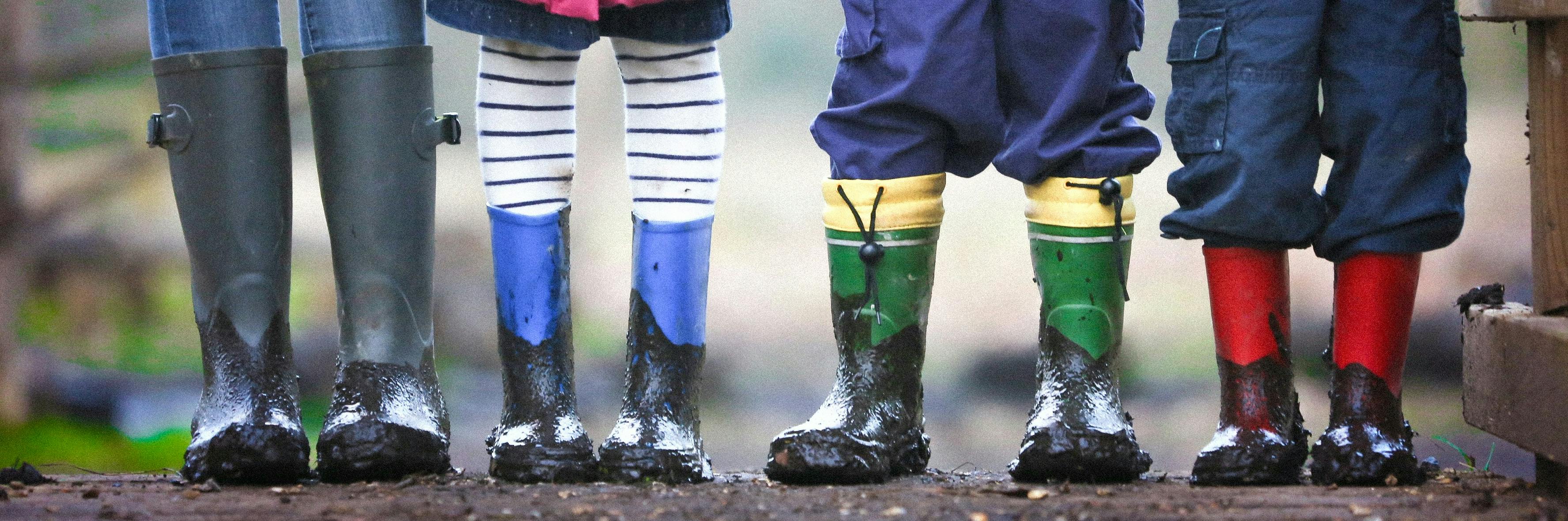 Children standing in line wearing wellington boots