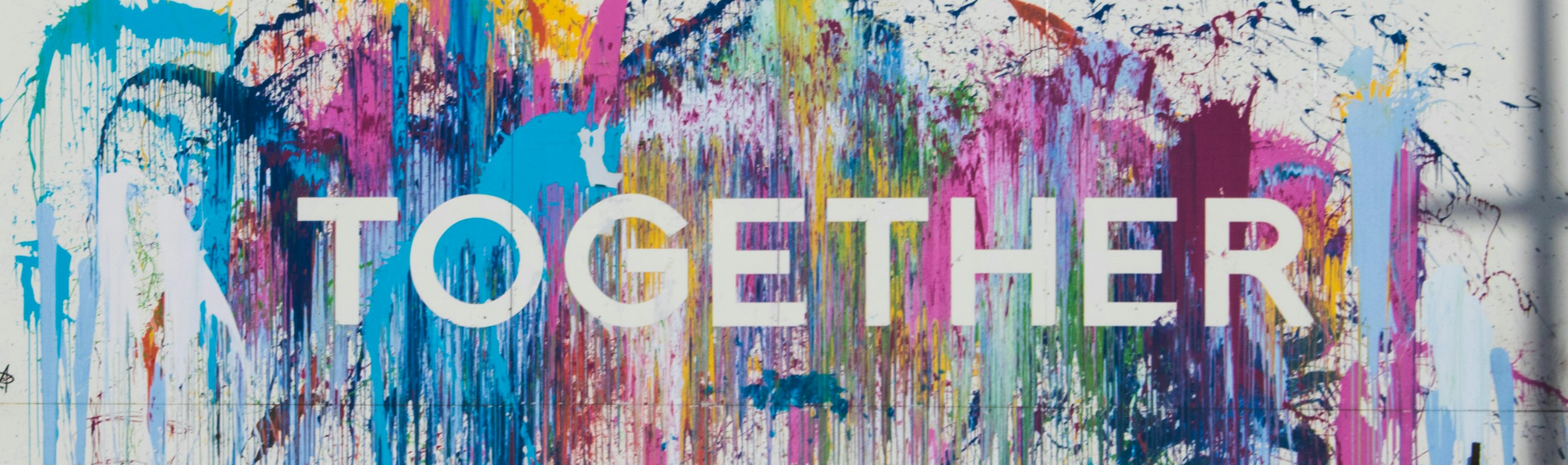 The word "Together" painted onto a wall on top of colourful splashes of paint