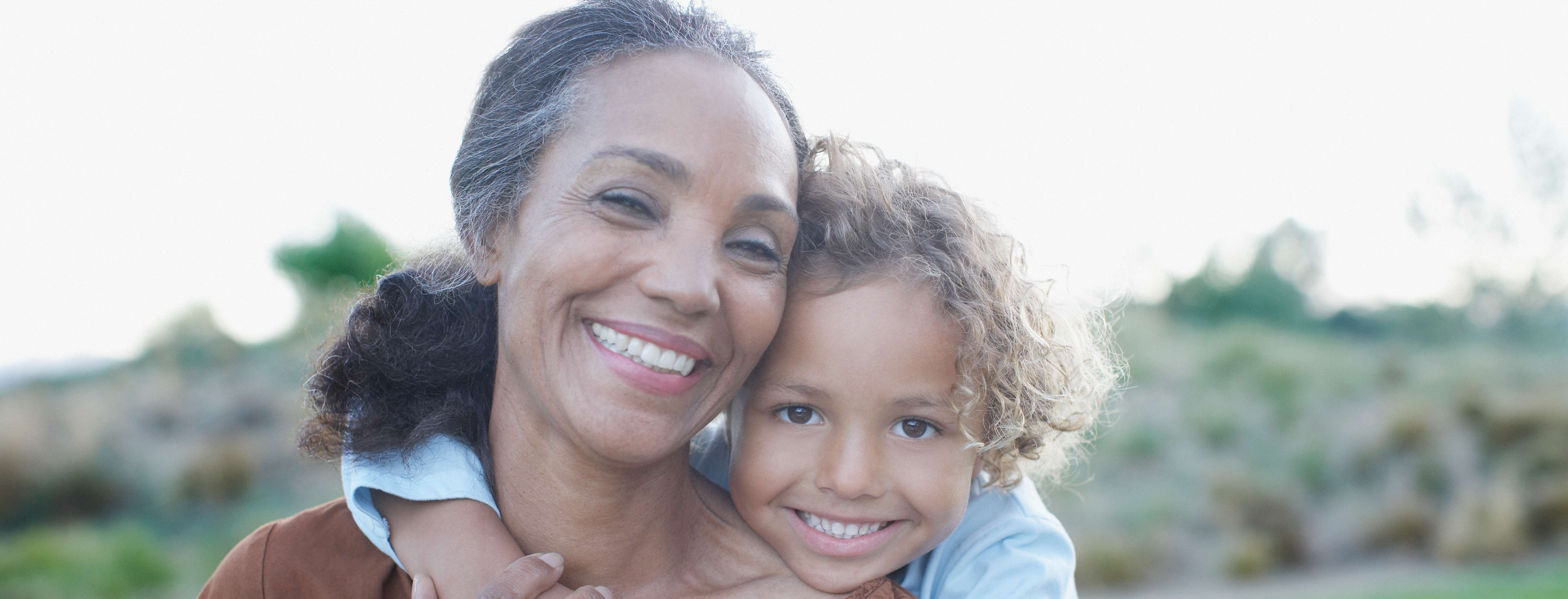 Older woman being hugged round the shoulder by young child