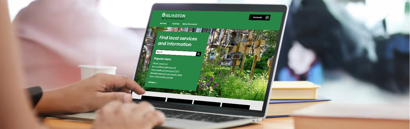 Hands on the keyboard of a laptop, typing. The Islington Council website is on the screen.