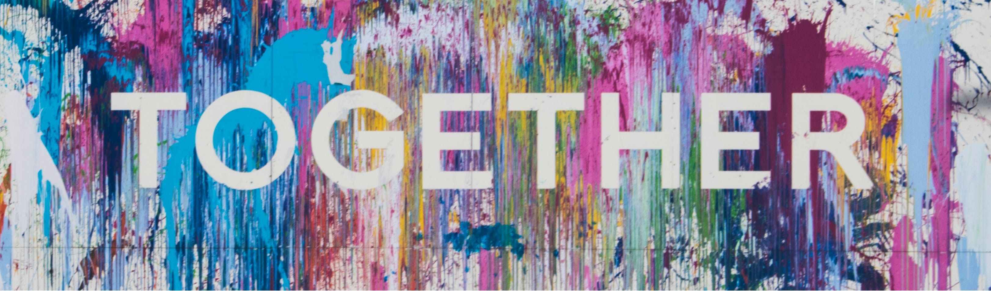 The word "Together" painted onto a wall on top of colourful splashes of paint