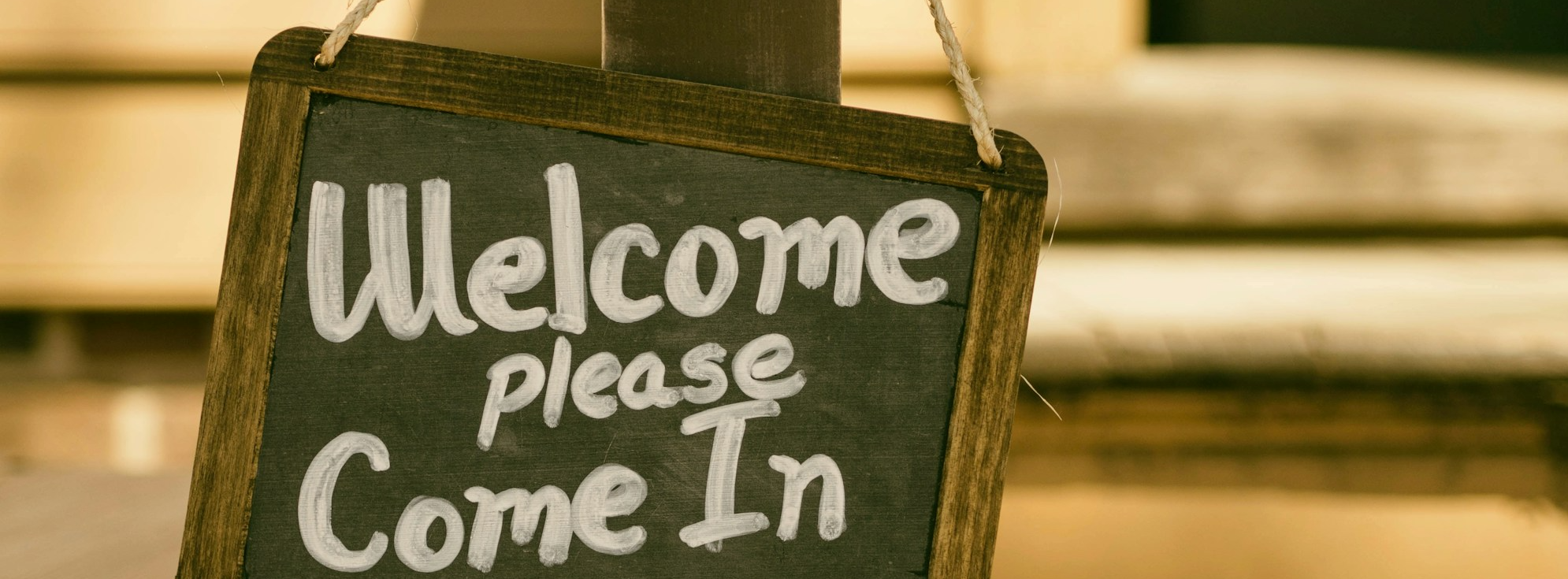 A chalkboard sign saying welcome please come in