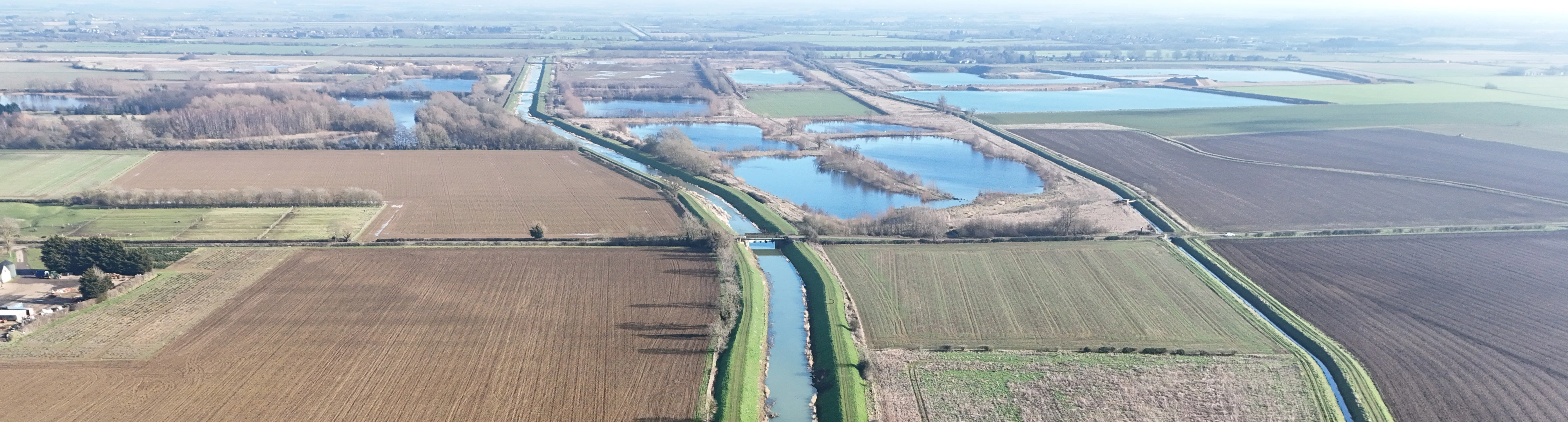 Drone photograph of the Maxey Cut. The Cut is central to the photo with farmland visible on either side.