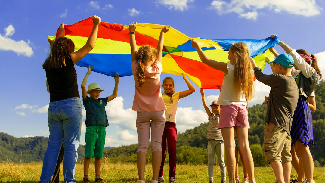 Happy children outside on grass playing a parachute game