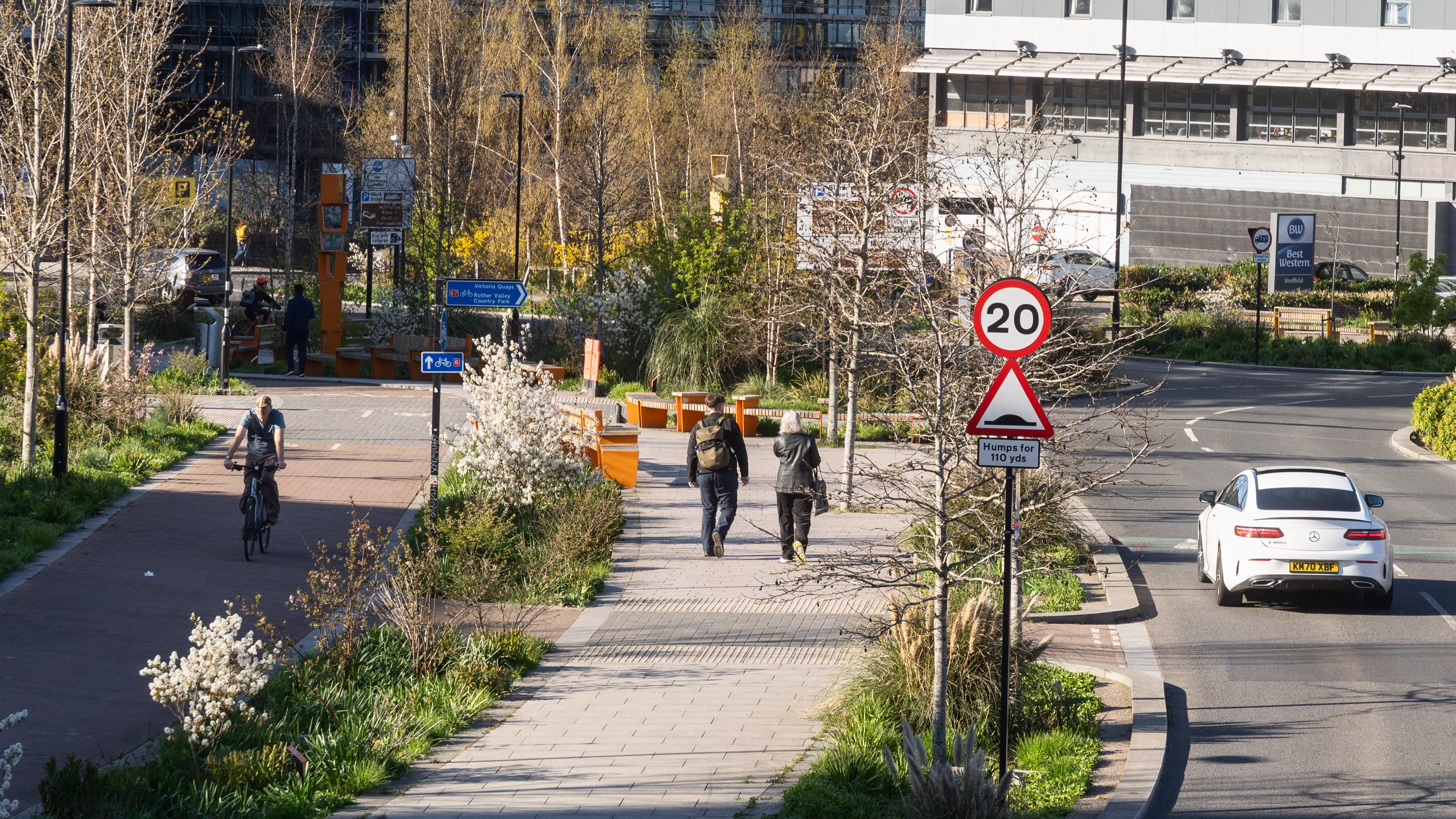 Image of an example of a cycle lane, next to a pedestrian walkway, next to a road. There is 1 bike, 2 pedestrians and 1 car