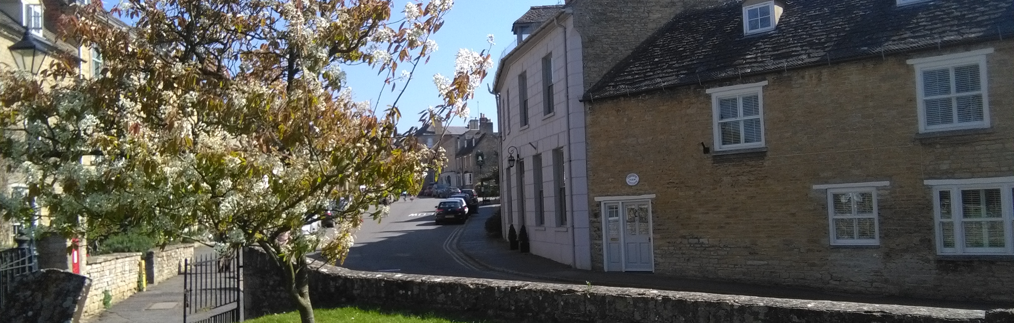 Cottages, tree in bloom and gravestones in Charlbury