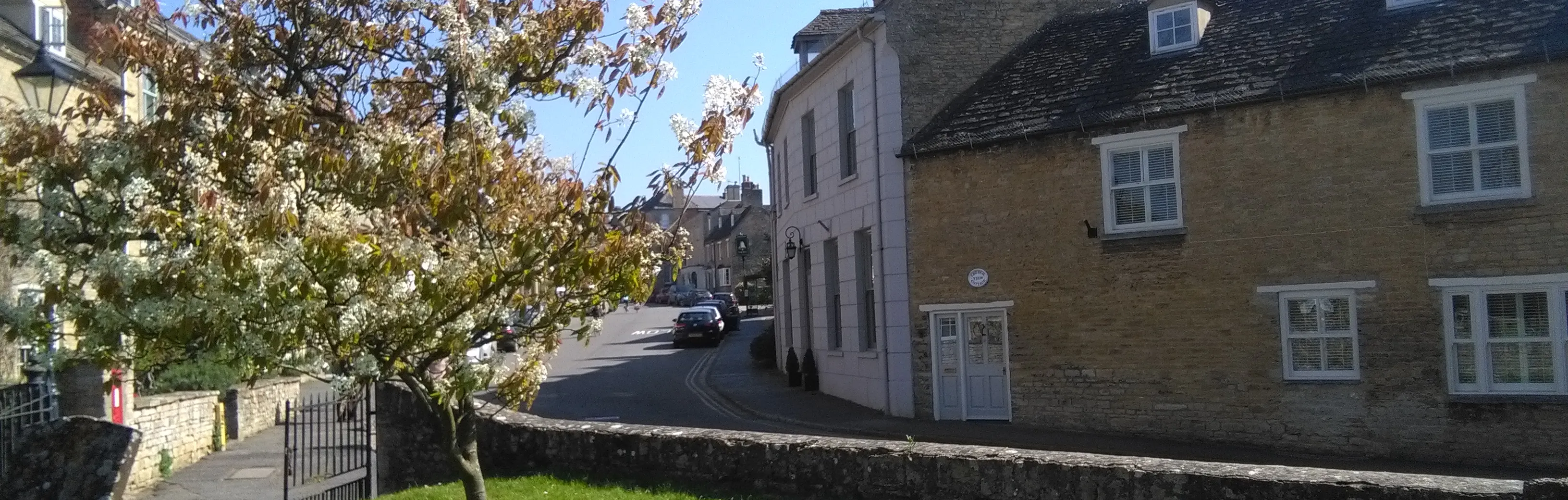 Cottages, tree in bloom and gravestones in Charlbury