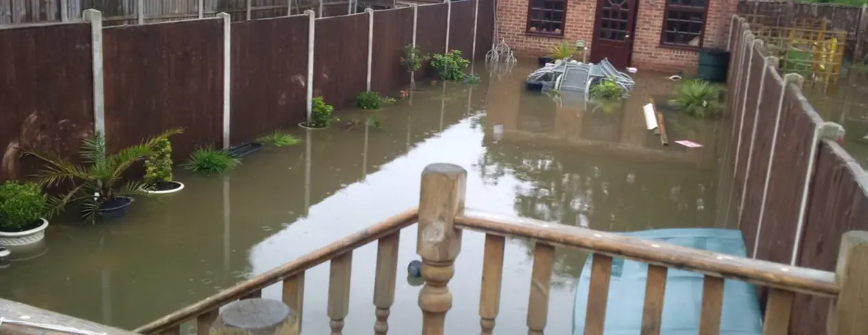 A picture of flooded garden in Havering. The water reaches up to the fence panels and submerging the plant pots.