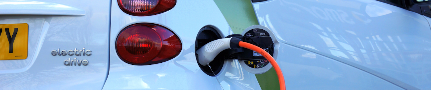 Image of a white electric car plugged into a charging point