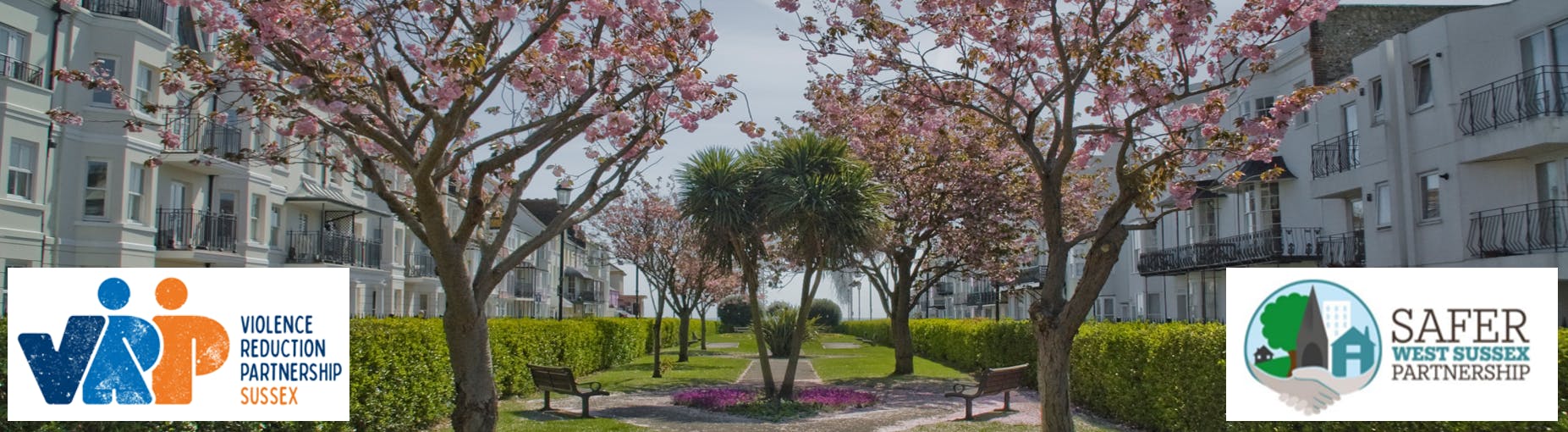 Pathway between cherry blossom trees and houses and the Violence Reduction Partnership Sussex logo and Safer West Sussex logo