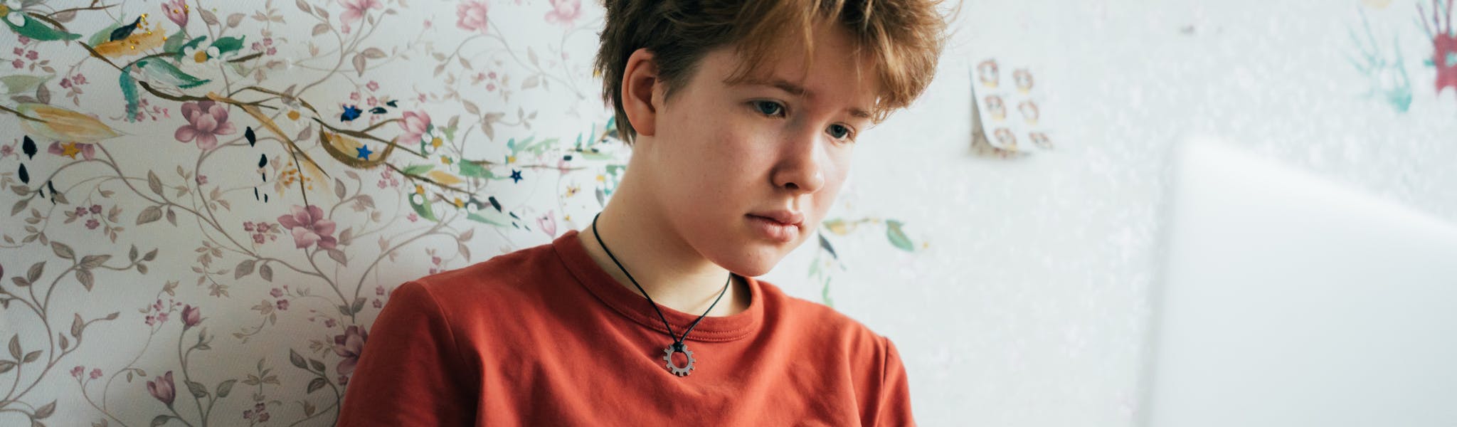 An image of a girl sitting in a room in front of a laptop