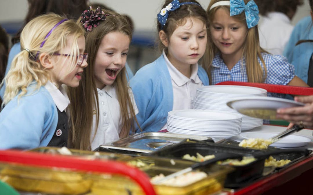 Children queuing up for school dinner in the school canteen