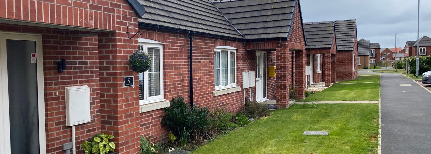 A row of bungalows with grass in front of them.