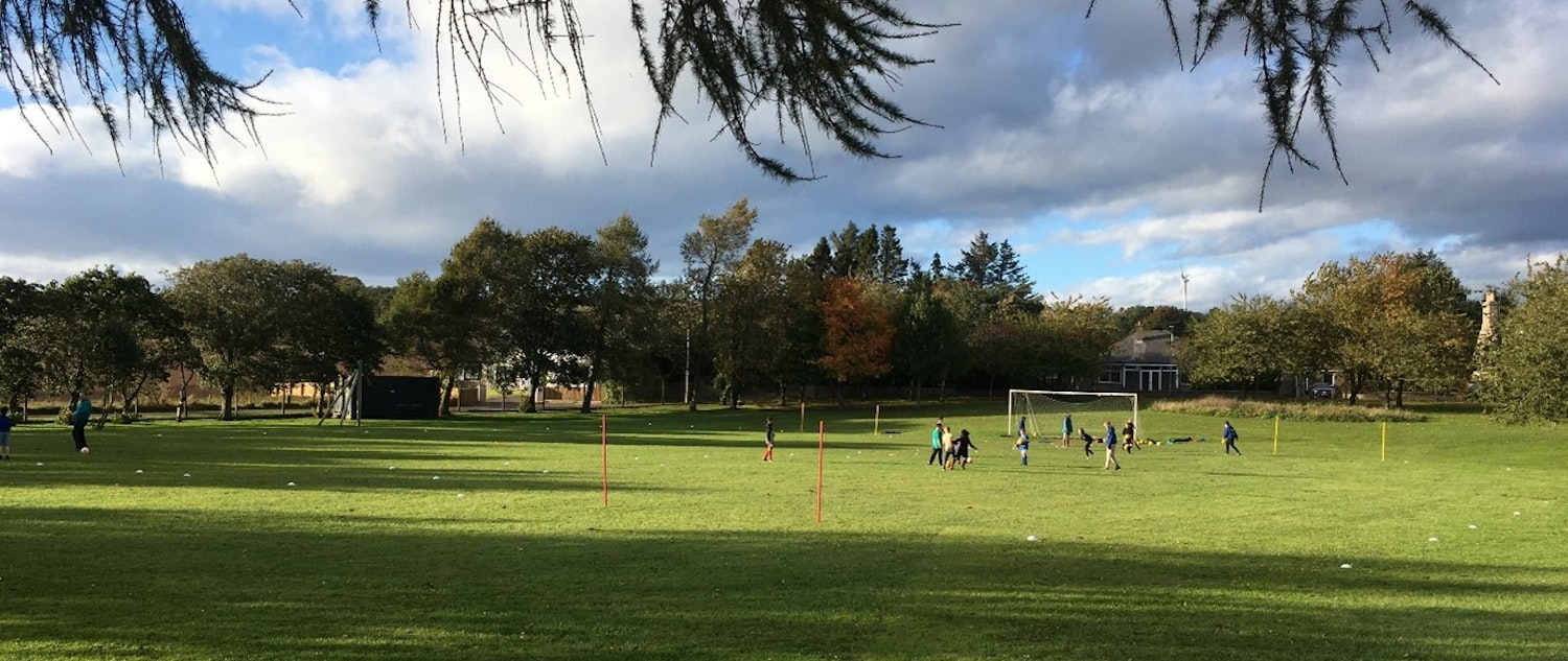 A field of grass with people playing football in Drumlithie