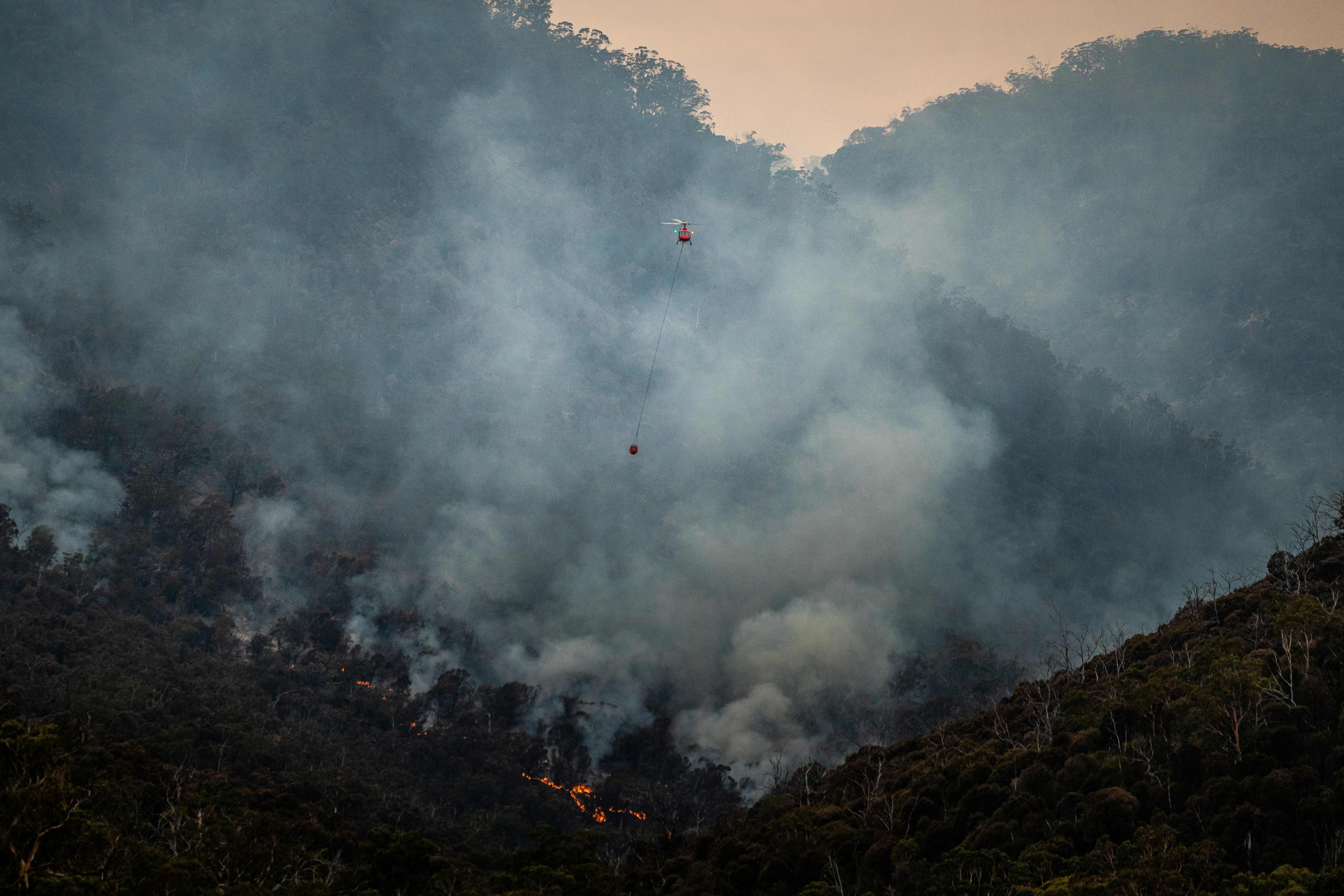 Helicopter water drop over a forest fire
