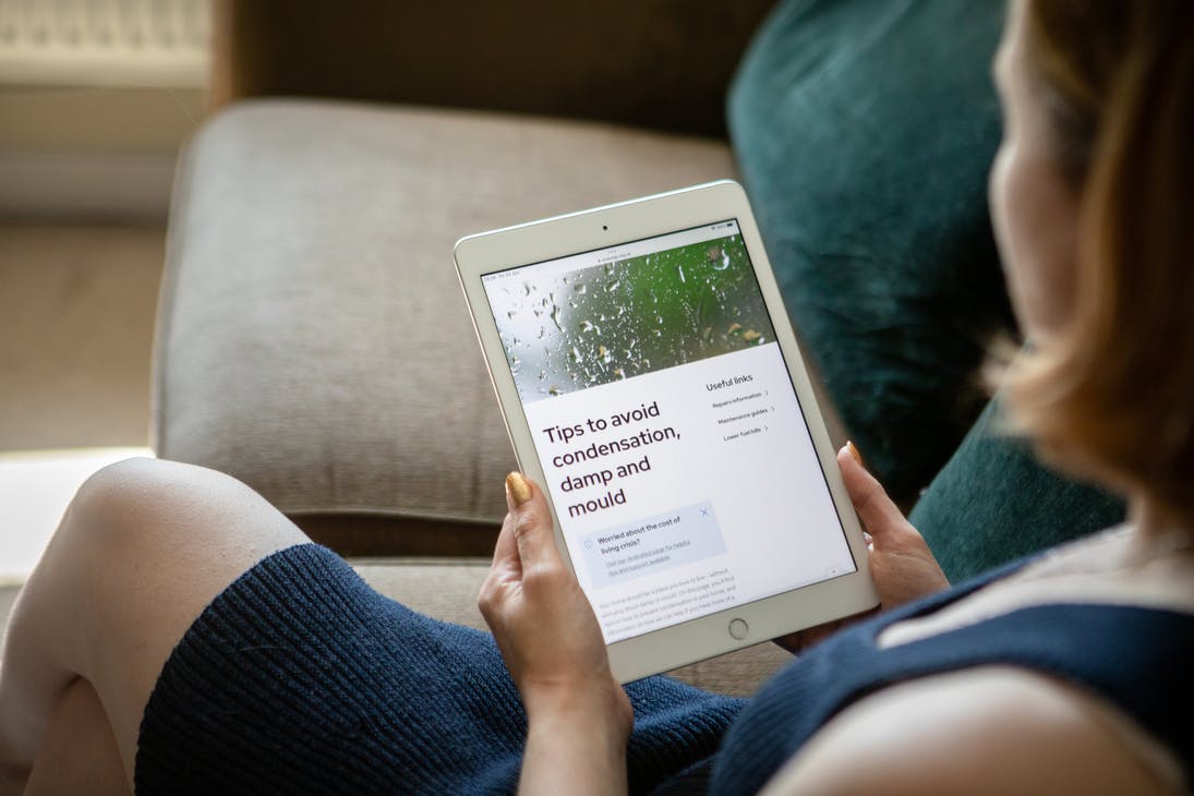 Resident reading SNG's tips to avoid condensation, damp and mould guide on a tablet