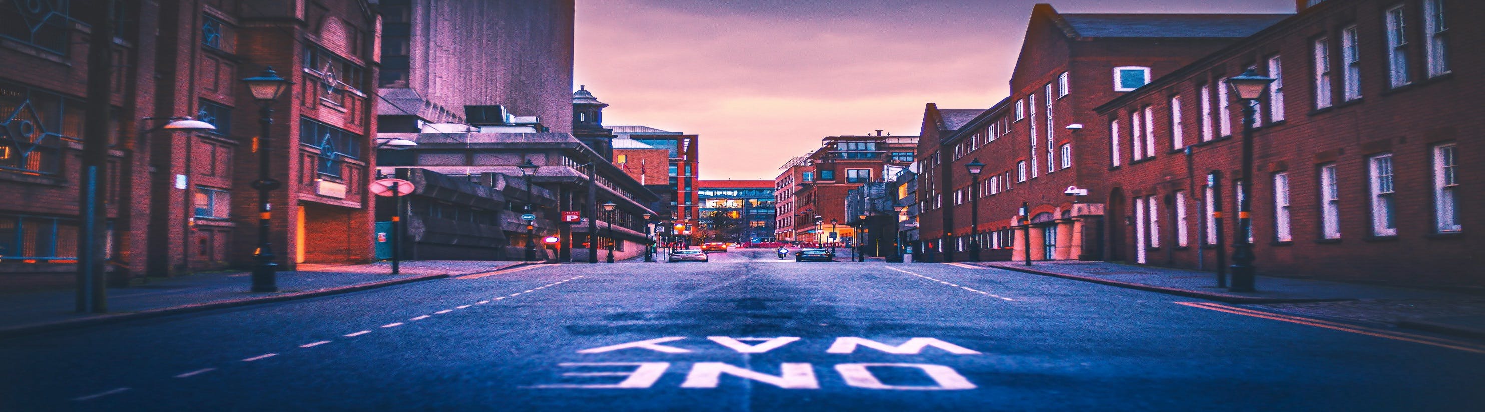 Photo of empty road with One Way painted on surface.