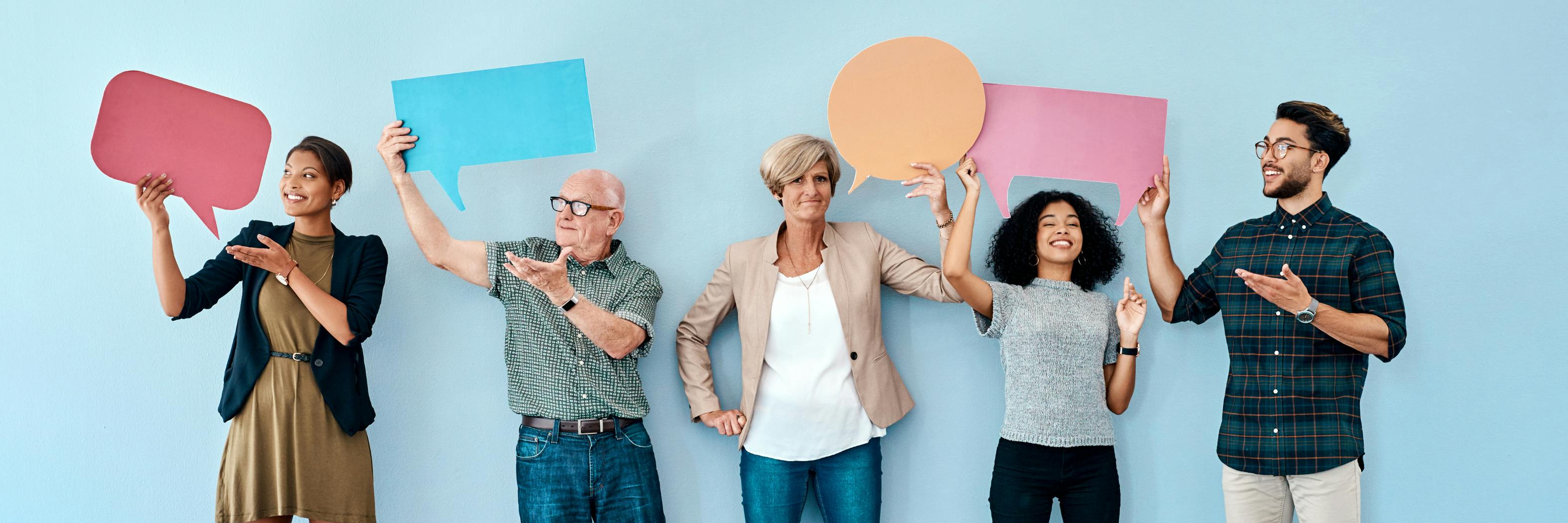 Image shows group of people holding up blank speech signs