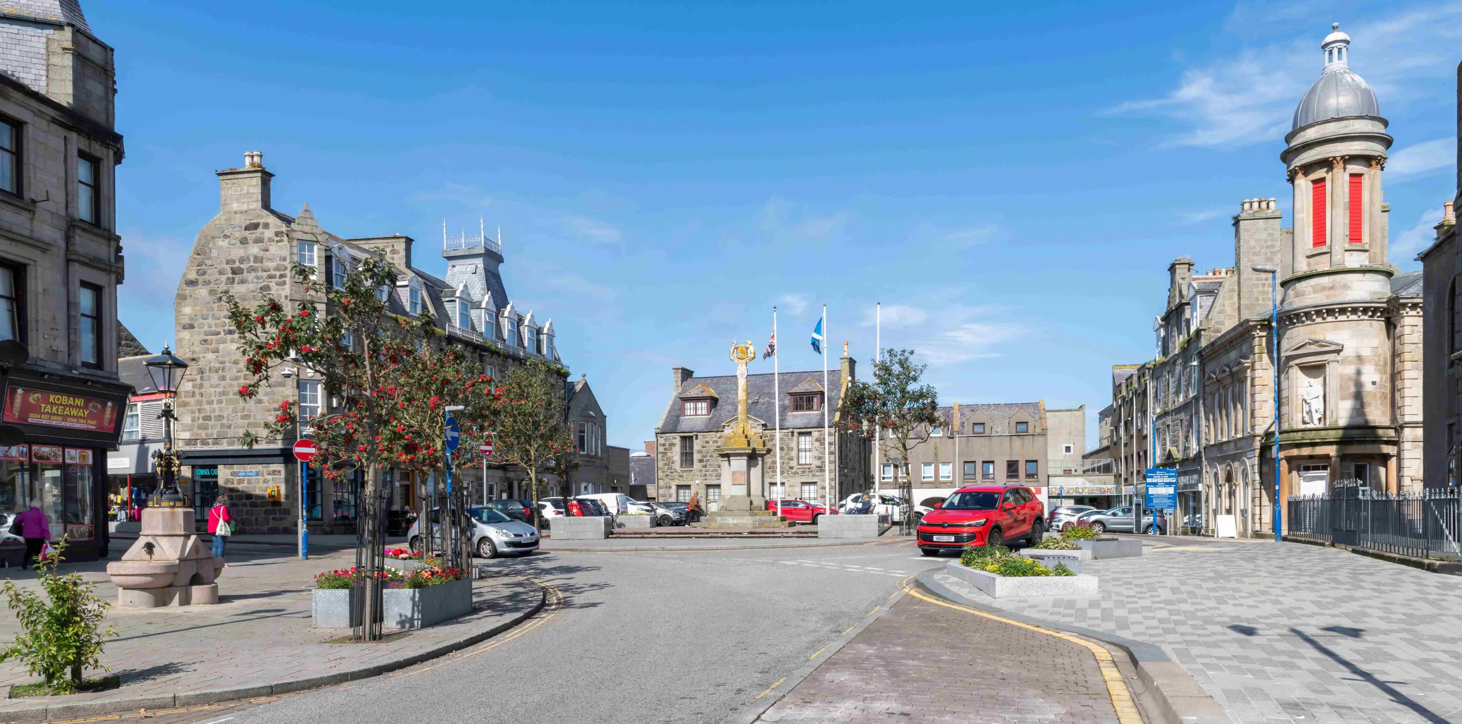 Image of Fraserburgh town centre with shops, trees, lampposts, people, road and pavement with the Fraserburgh BIG Ideas logo