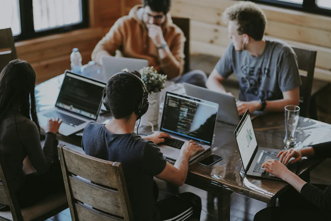 Group of 5 people at laptops around a table