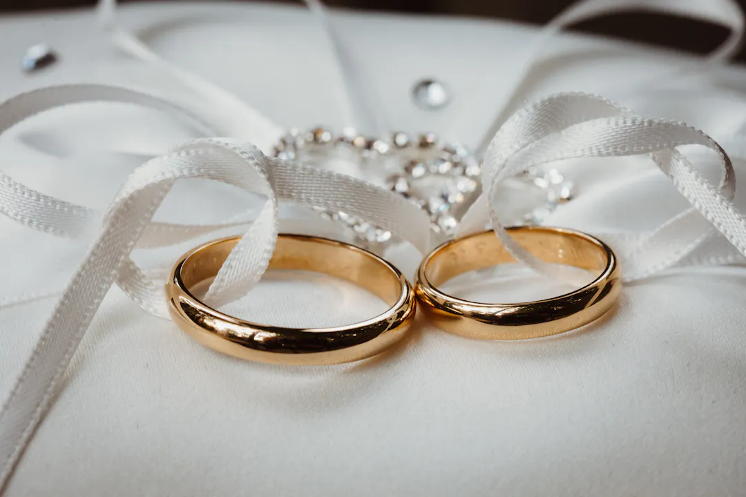 Two wedding rings on a cushion with ribbon