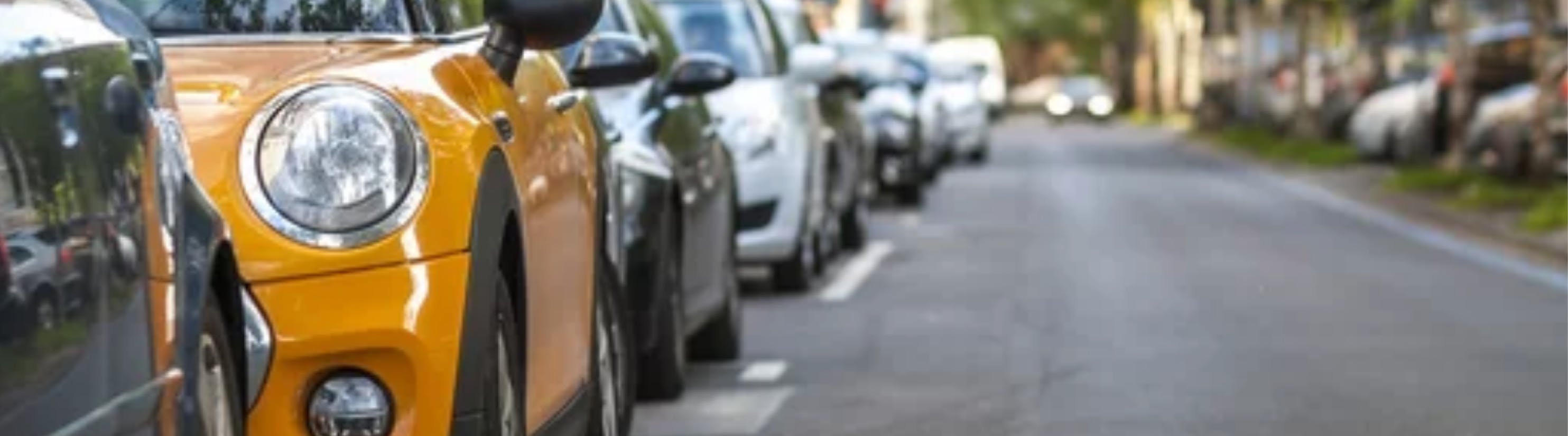 Photo of cars parked on left hand side of road.