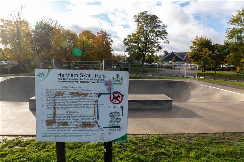 a boy on a skateboard in a skatepark holding hands with a man