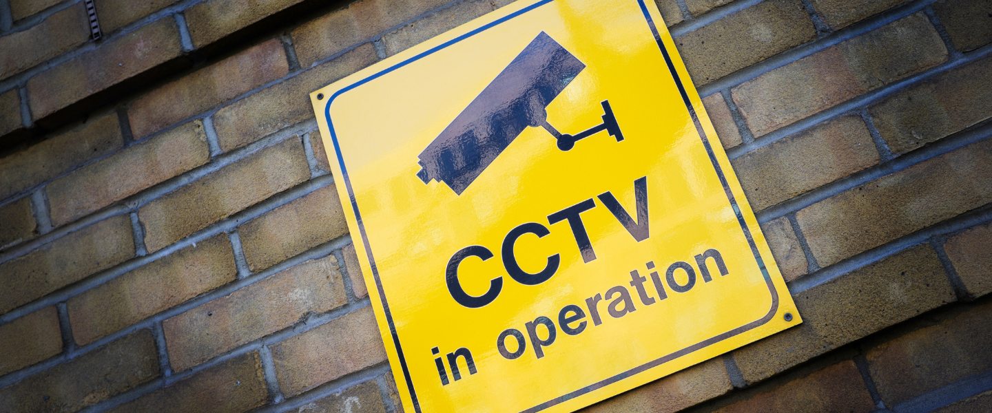 Yellow CCTV in operation sign on a brick wall.