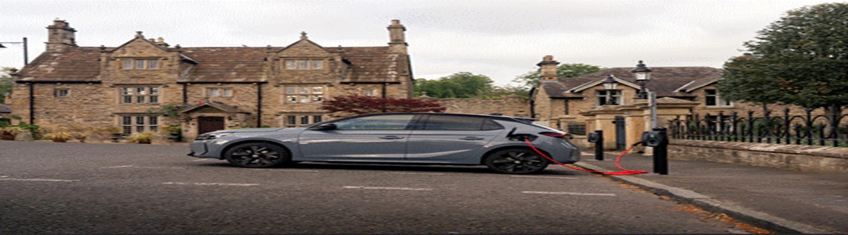 Photo of grey car being charged via red cable from a lamp-column charging point. 