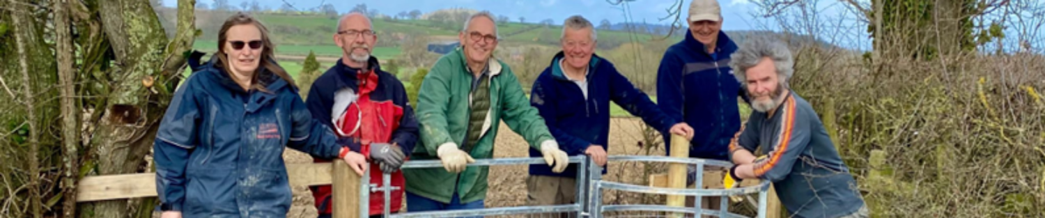 Six volunteers standing next to a recently built fence and gate