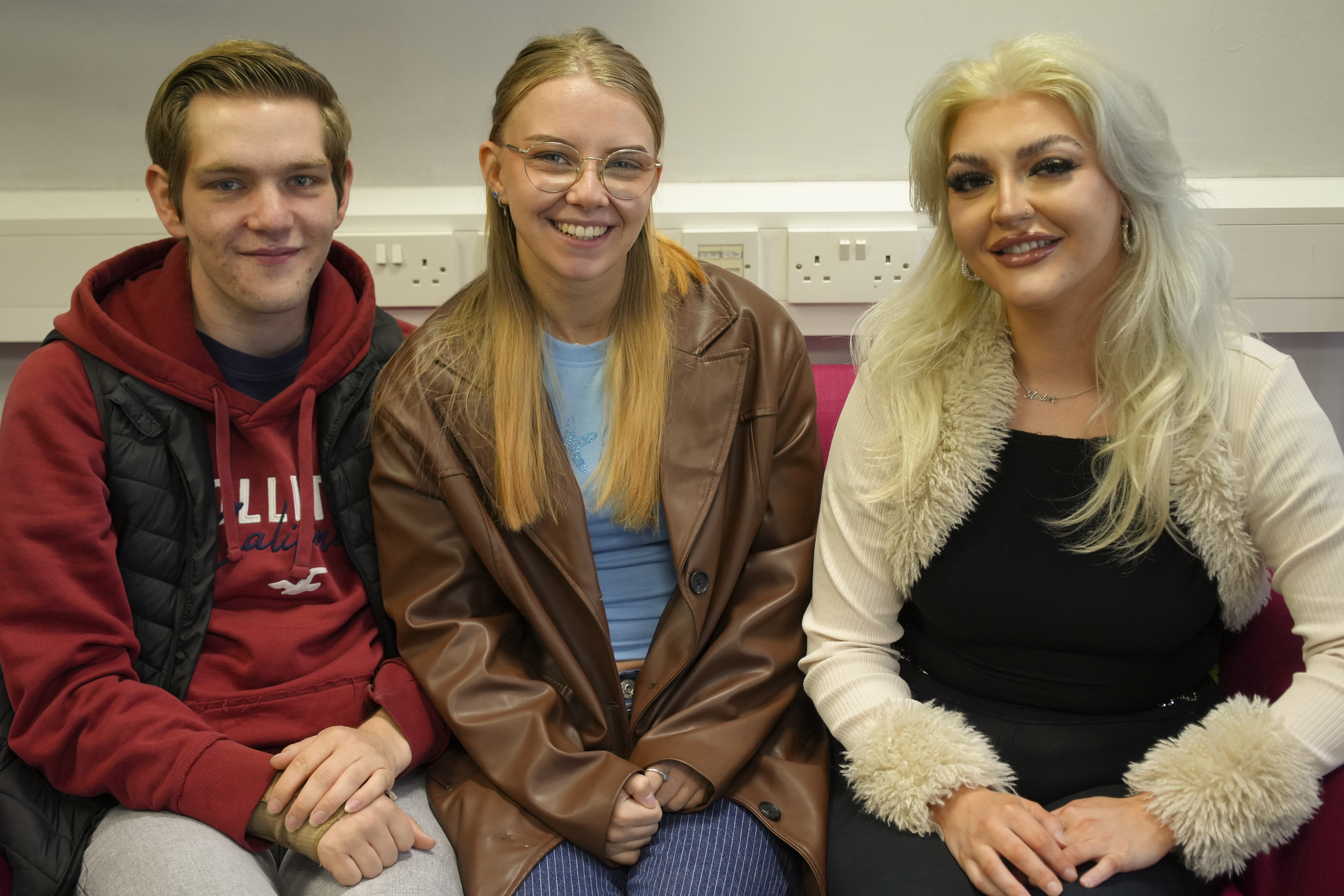 3 people sat on a coach, smiling