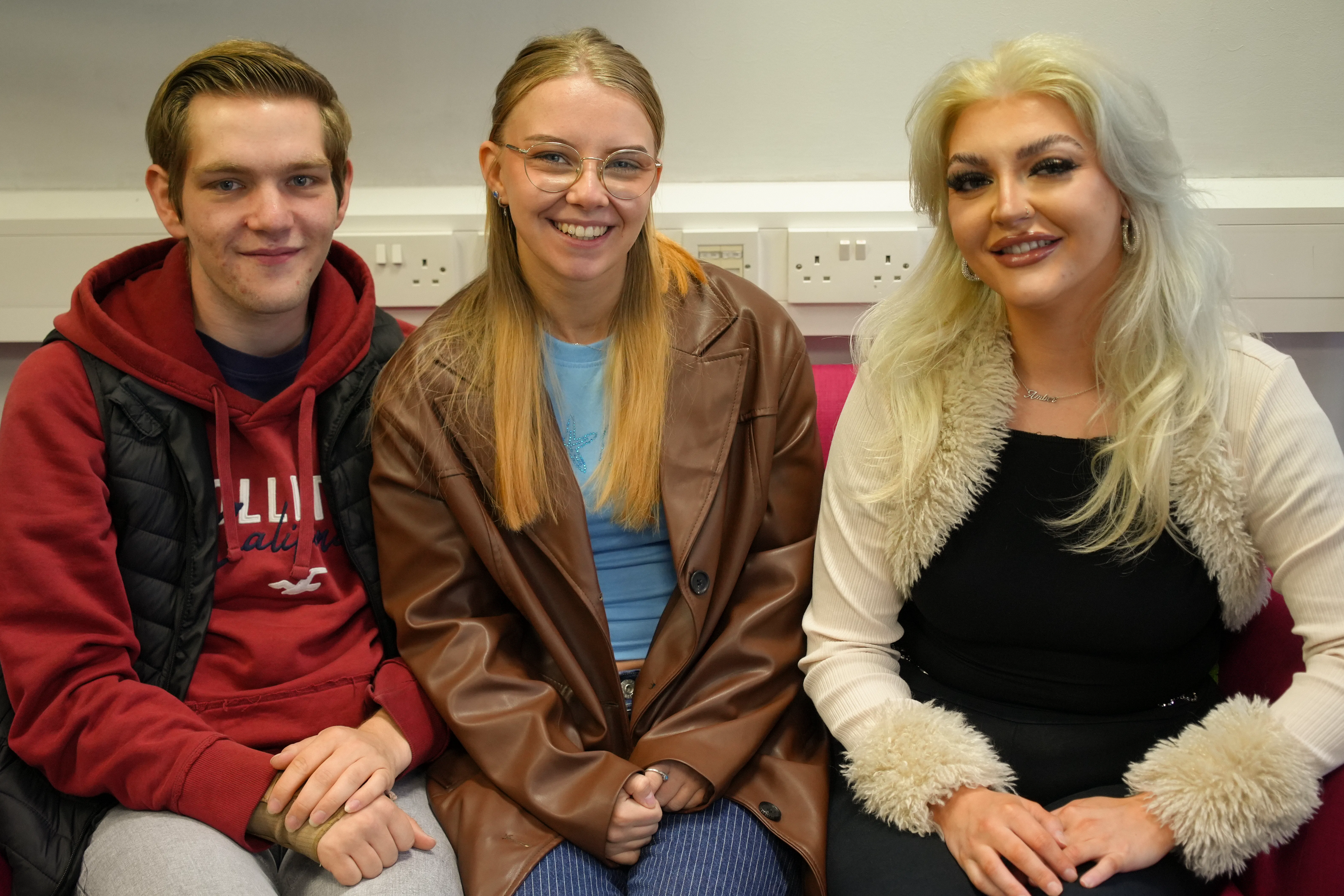 3 people sat on a coach, smiling