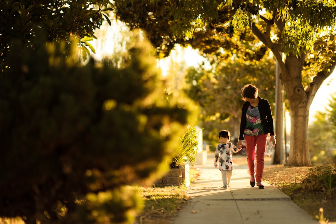 Female foster carer with young child waking along a wooded path