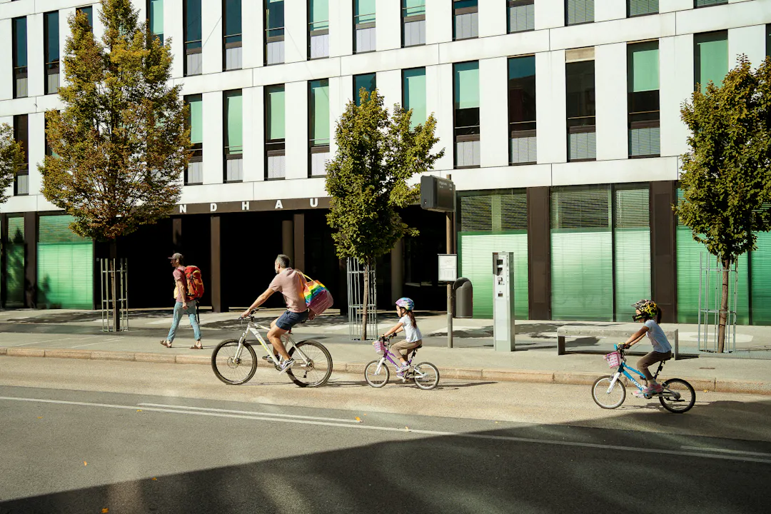 Image shows a family on bikes riding by a building